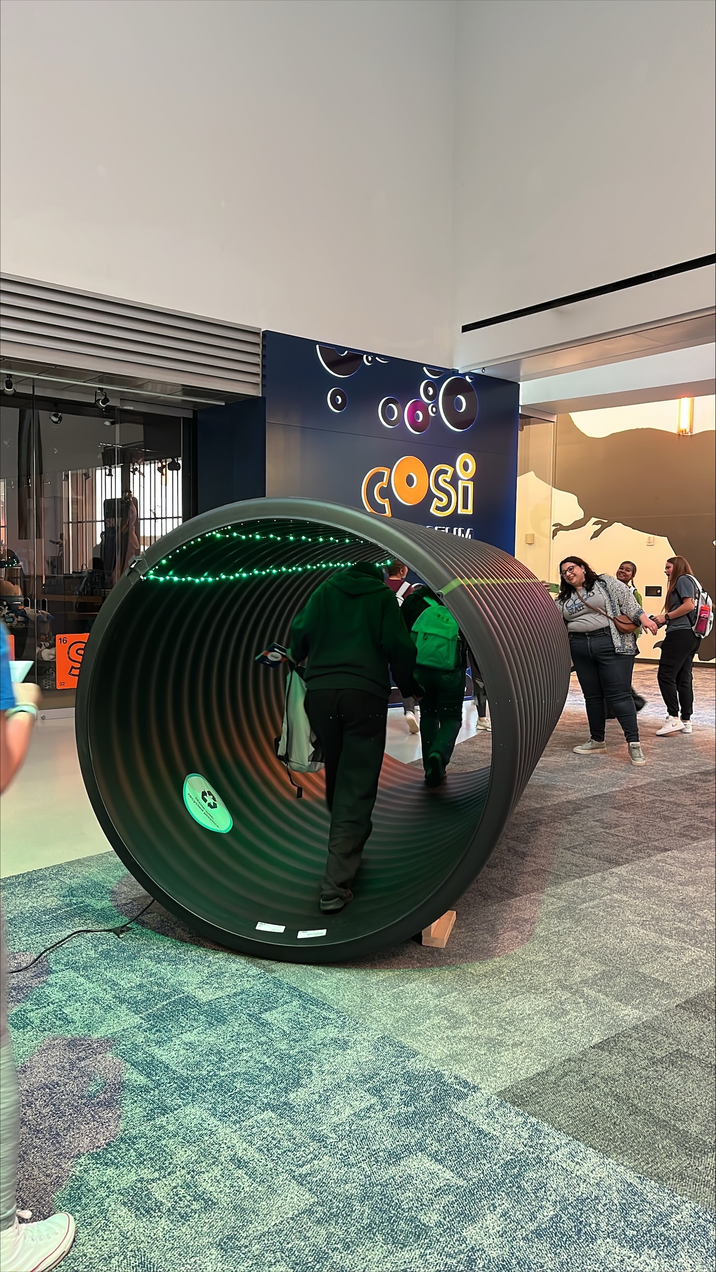 Students walking through a black plastic corrugator stick of Advanced Drainage Systems pipe.