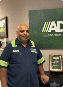 ADS employee standing in front of a cabinet and wall-mounted signage